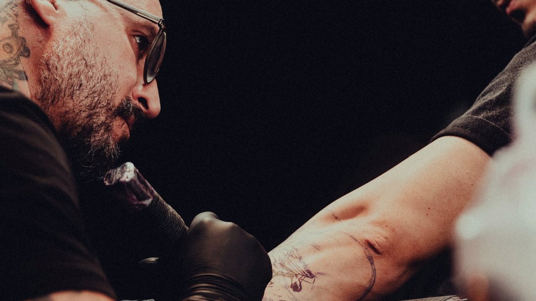 Tatuador trabalhando em um braço durante evento no estúdio