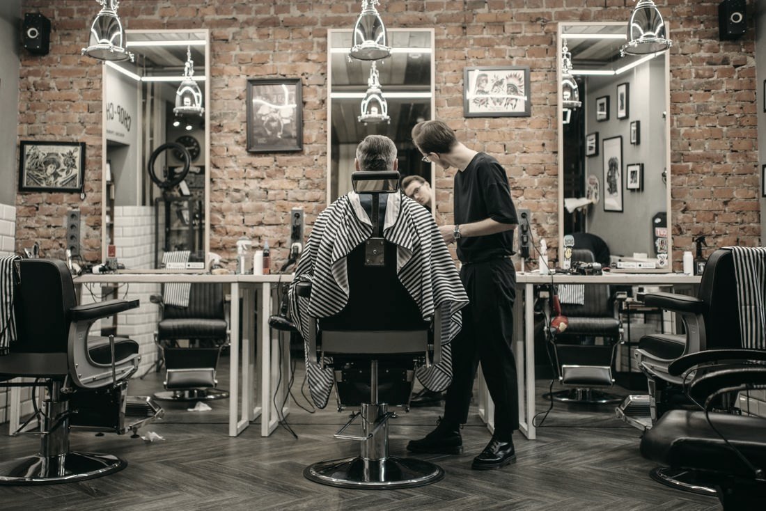Interior de barbearia com parede de tijolos e madeira