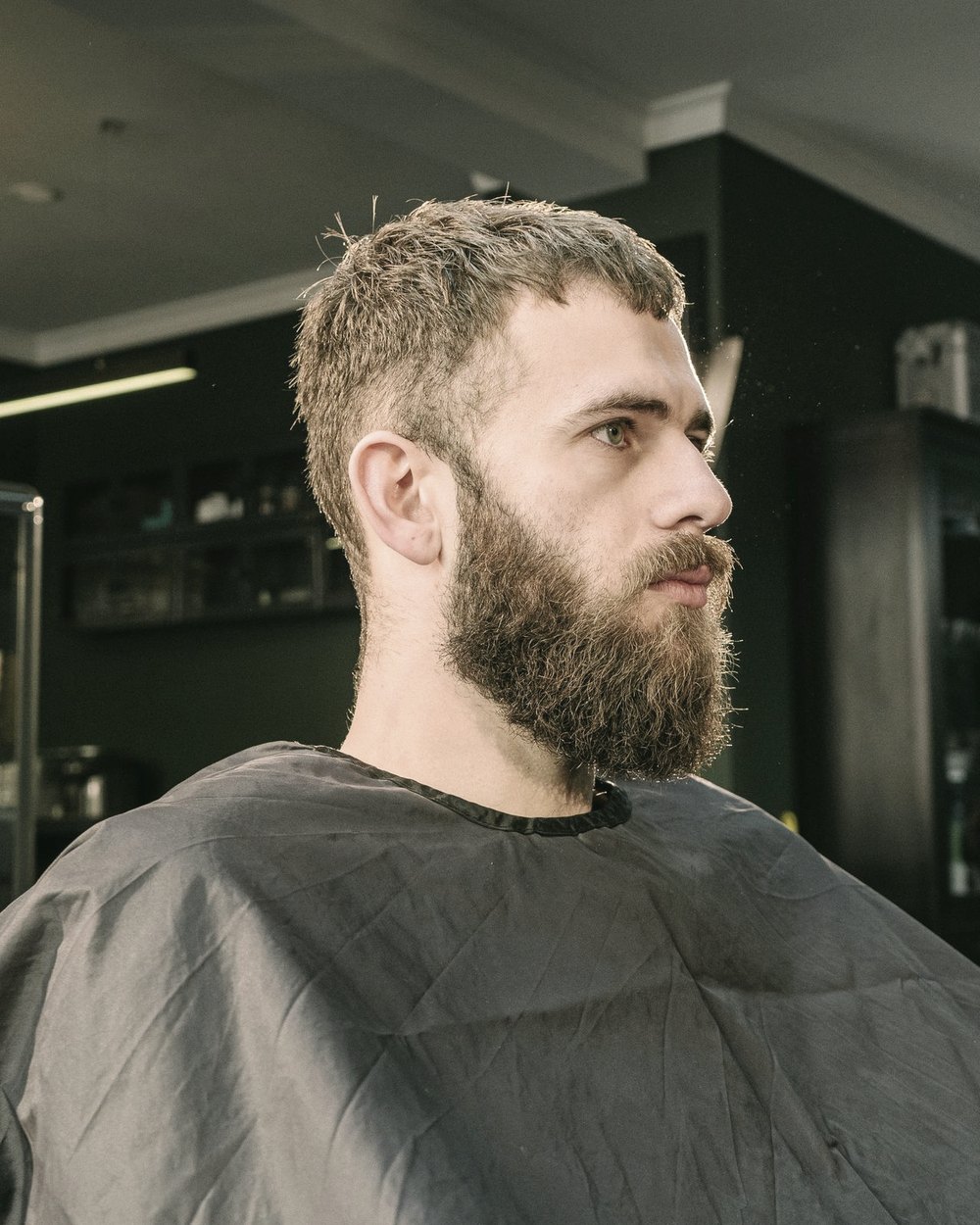 Homem barbudo sentado em barbearia moderna