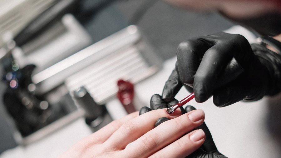Manicure aplicando gel em unhas de cliente