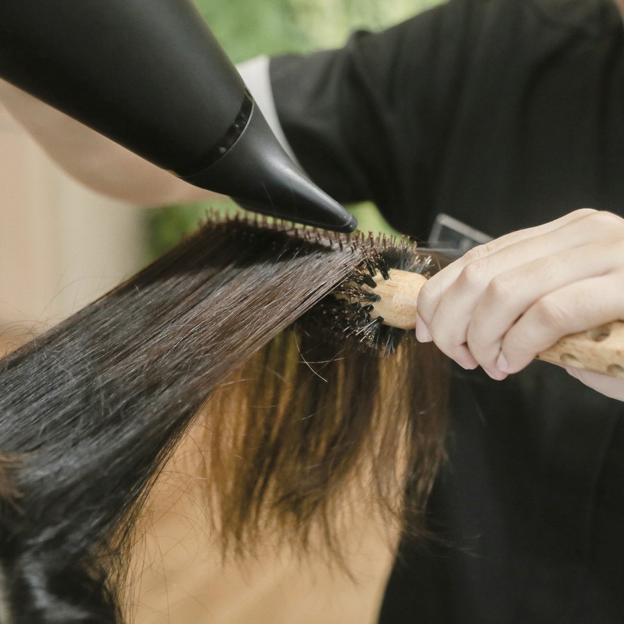 Cabeleireira finalizando o cabelo de uma cliente