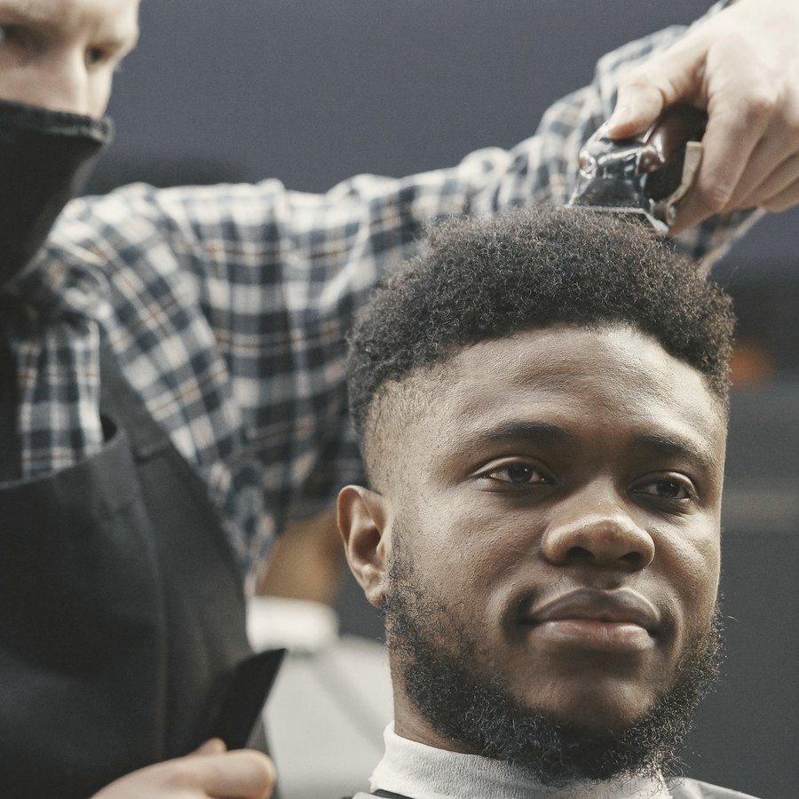 Barbeiro cortando o cabelo de um cliente que sorri