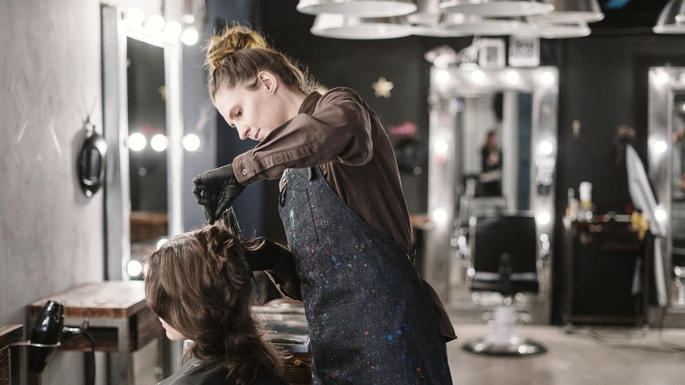 Cabeleireira trabalhando no cabelo de uma cliente