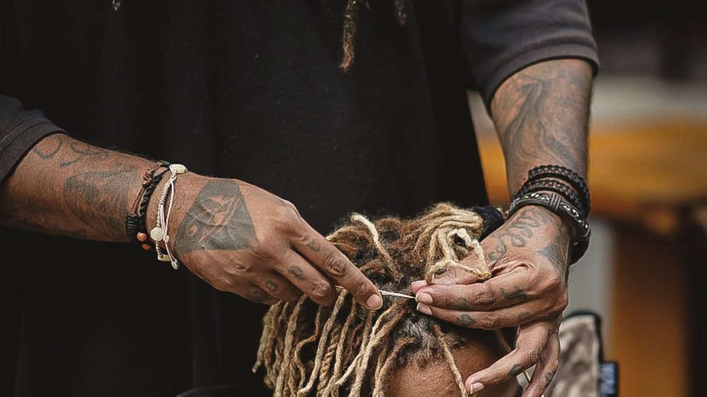 Mãos trançando dreadlocks no cabelo de uma pessoa