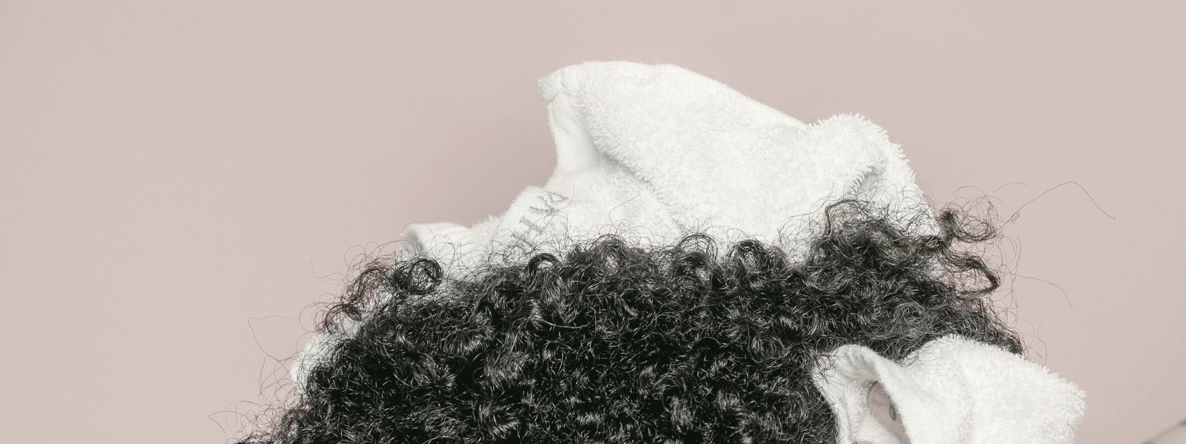 Cabelo cacheado sendo enrolado na toalha após a lavagem