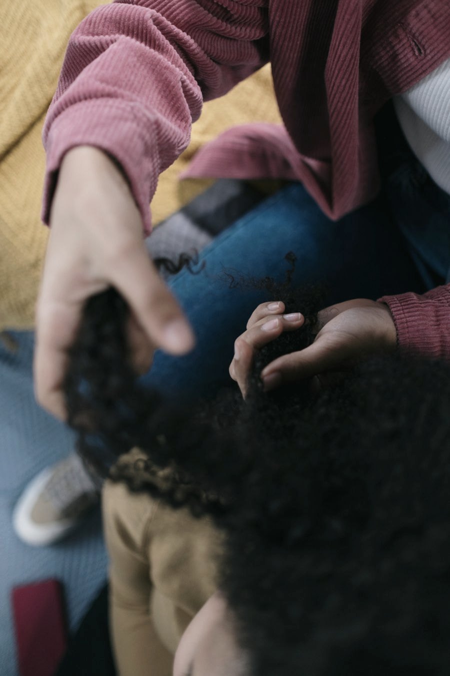 Mãos segurando mecha de cabelo cacheado, em close
