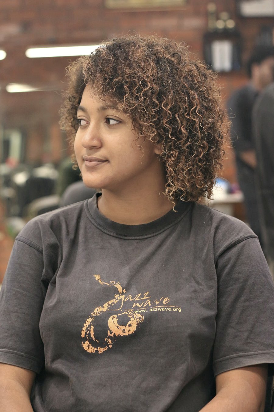 Jovem de cabelo crespo volumoso em ambiente iluminado