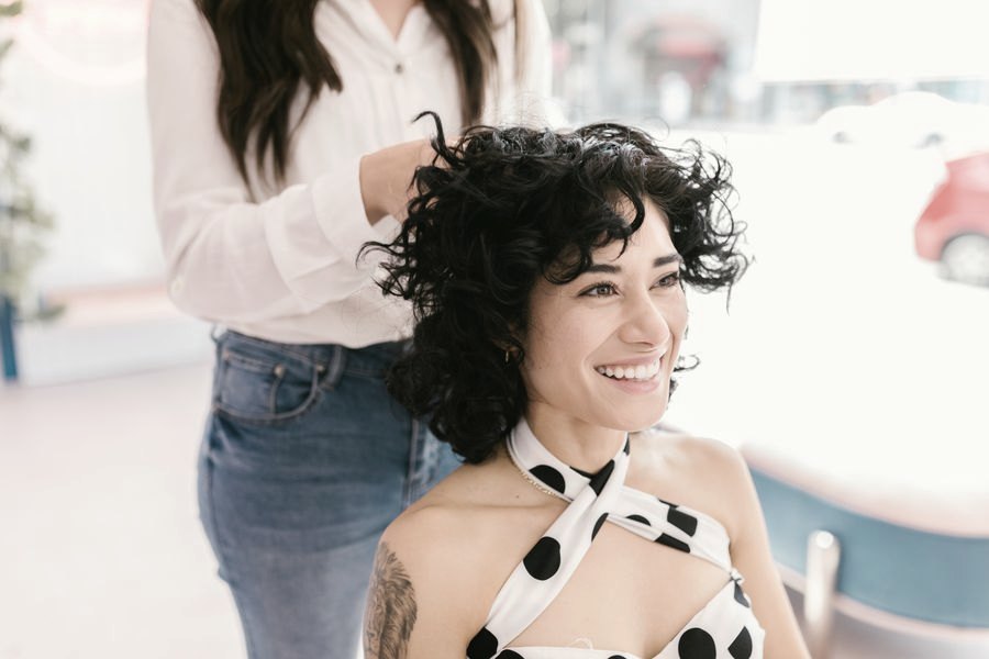 Cabeleireira e cliente sorrindo durante o atendimento