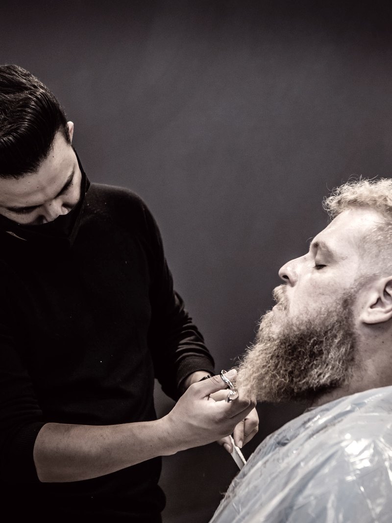 Barbeiro alinhando a barba de um cliente
