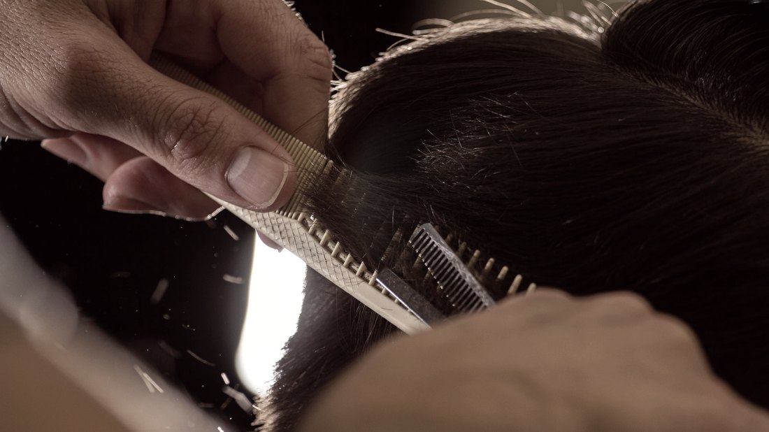 Barbeiro em detalhe, trabalhando com pente e tesoura