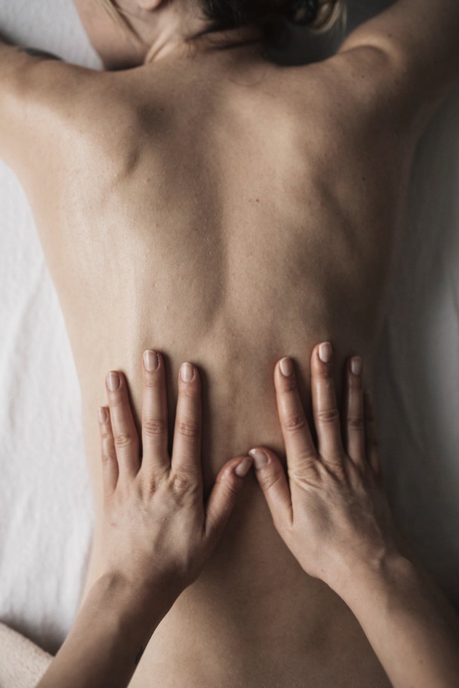 Mãos aplicando massagem na região lombar