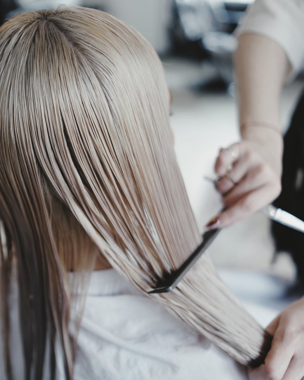 Cabeleireira ajustando o comprimento de um cabelo loiro no salão
